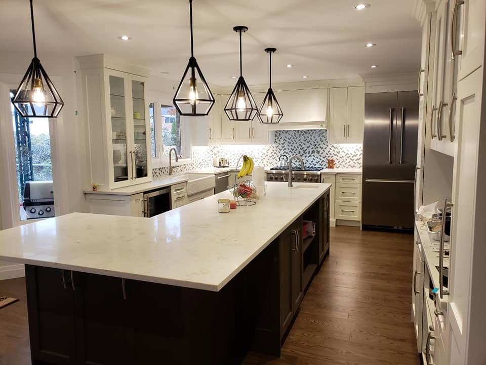 White kitchen with a dark island and geometric pendants by LG Woodworking